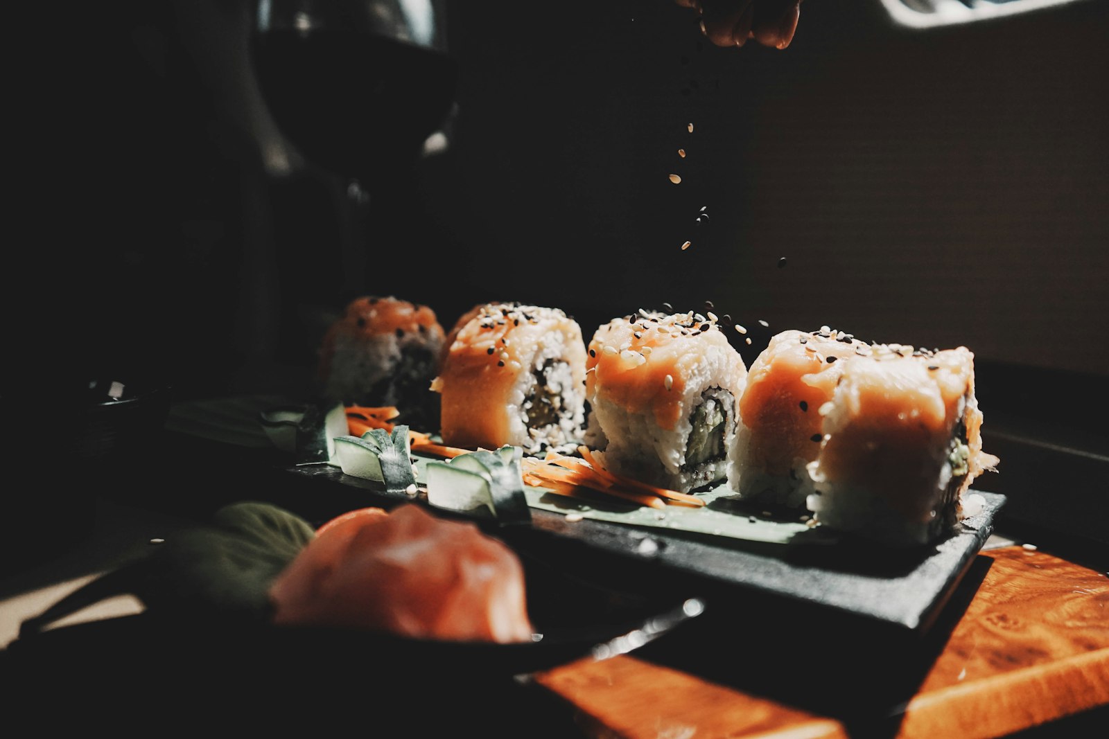 A close set of freshly pressed nigiri sushi on a dark counter, glistening under warm light